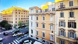 En byggnad med flera våningar, en gul fasad, vita fönsterramar och en balkong på översta våningen.
