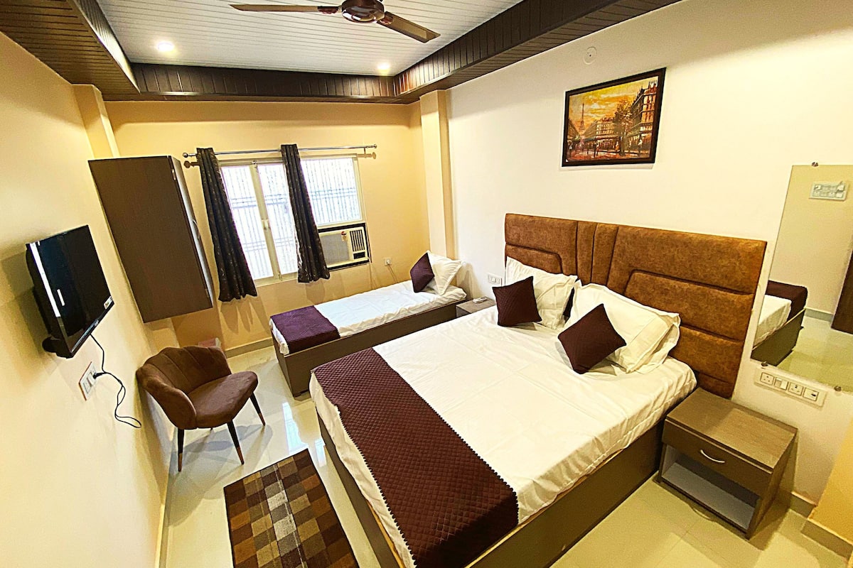 Una habitación de hotel con cama, escritorio, silla, televisor y ventilador de techo.