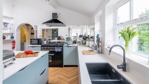 A modern kitchen with a central island, a built-in oven, a microwave, and a sink. - Cliff Lane House, Cromer, Norfolk (Cromer)