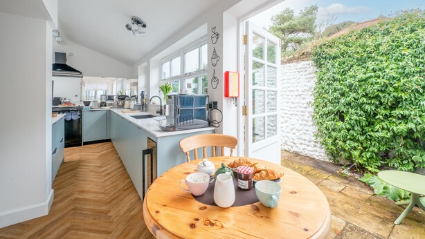 A kitchen with a dining area, a view of the garden, and a large window. - Cliff Lane House, Cromer, Norfolk (Cromer)