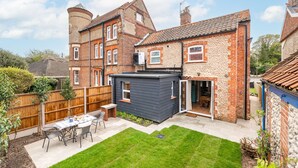 A residential property with a backyard patio, a small shed, and a brick house with a tiled roof. - Mollie's Cottage, Overstrand, Norfolk (Overstrand)