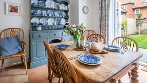 A dining table set with blue and white plates, a vase with flowers, and a bread basket. - Mollie's Cottage, Overstrand, Norfolk (Overstrand)