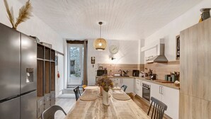Een moderne keuken met een houten eettafel, inbouwapparatuur en een hanglamp.