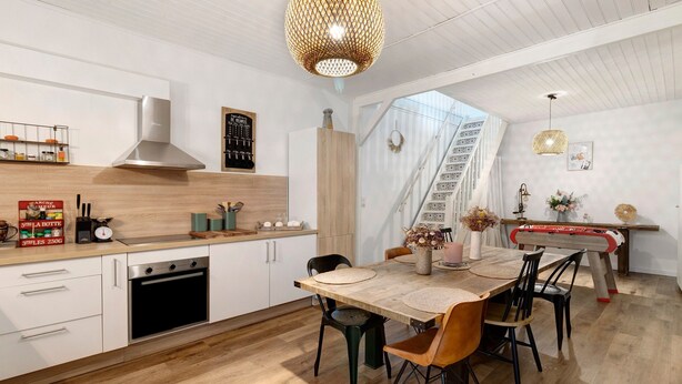 Een moderne keuken met een eethoek, houten vloeren en een trap naar een hoger niveau.