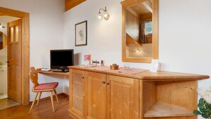 A wooden-framed room with a desk, a chair, a television, a mirror, and a framed picture on the wall.
