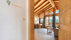 A wooden interior with a dining area, a sofa, and a window with curtains. - Apartment Margerite 21 with Mountain View and Wi-Fi (Santa Valburga)