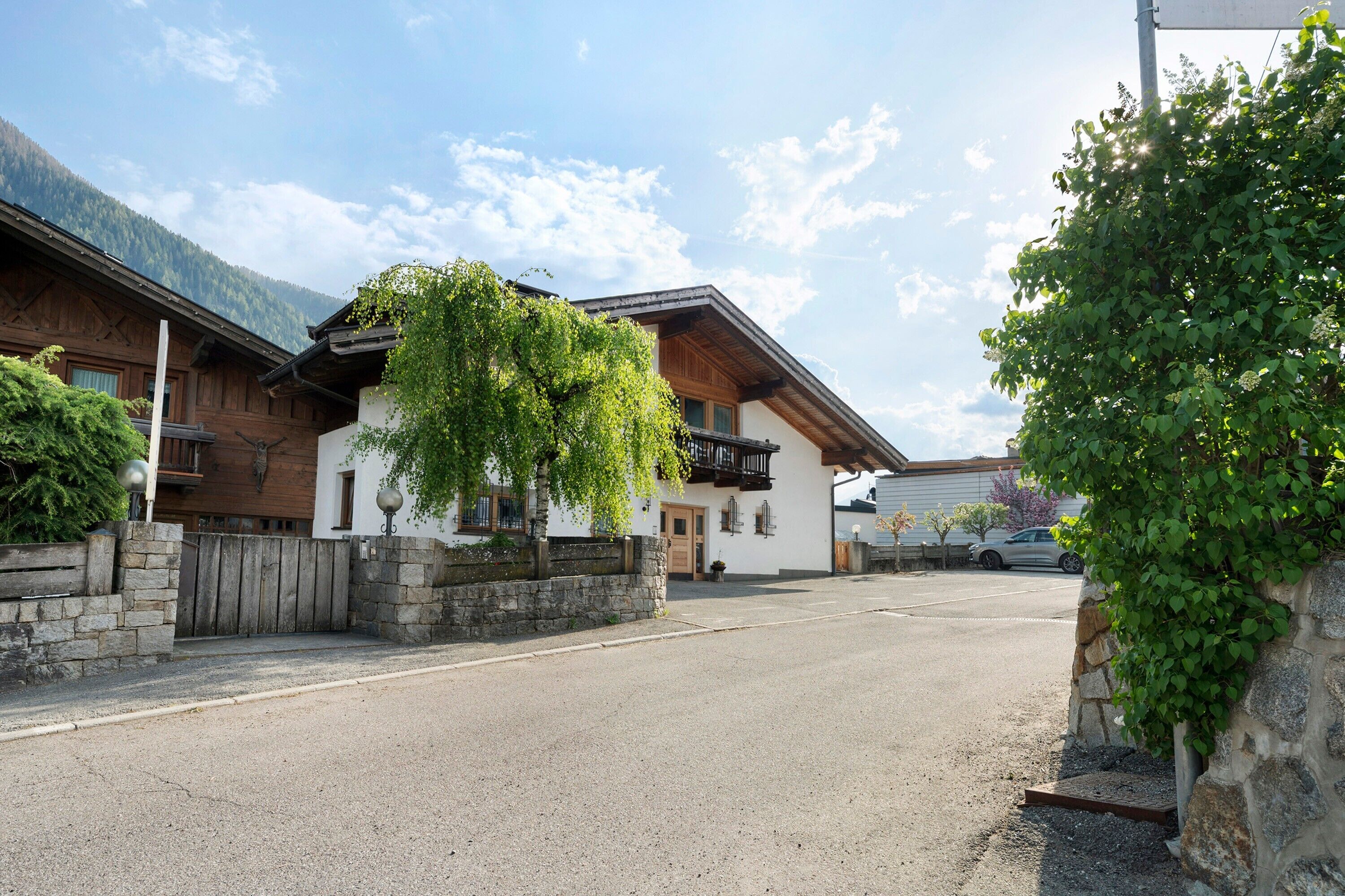 A street with traditional wooden houses, stone walls, and a clear sky.