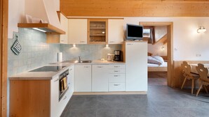A modern kitchen with white cabinets, a built-in oven, and a coffee maker. - Apartment Margerite 21 with Mountain View and Wi-Fi (Santa Valburga)