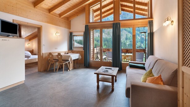 A wooden interior with a dining area, sofa, and a TV. - Apartment Margerite 21 with Mountain View and Wi-Fi (Santa Valburga)