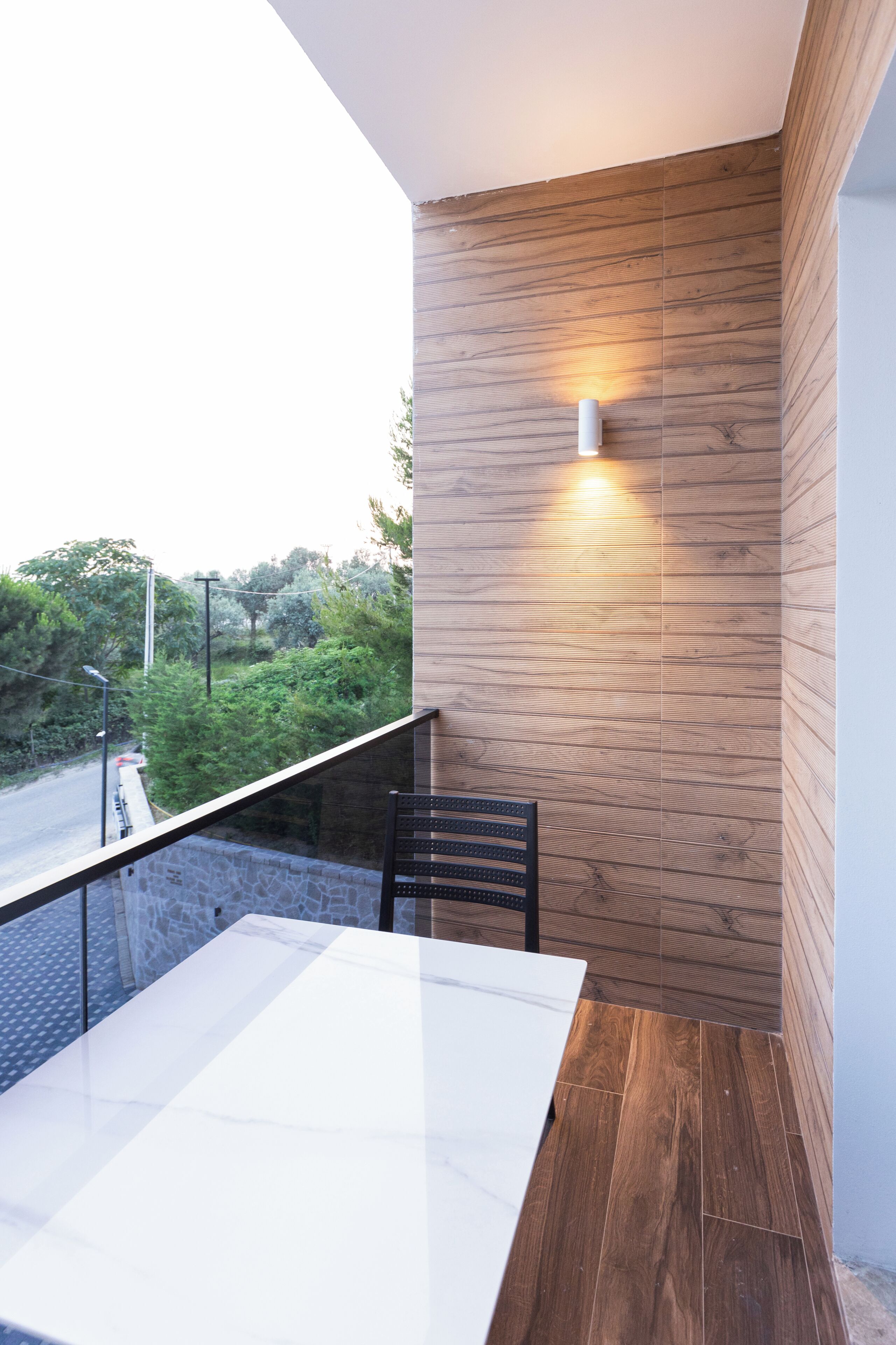 A balcony with a wooden wall, a table, and a chair.