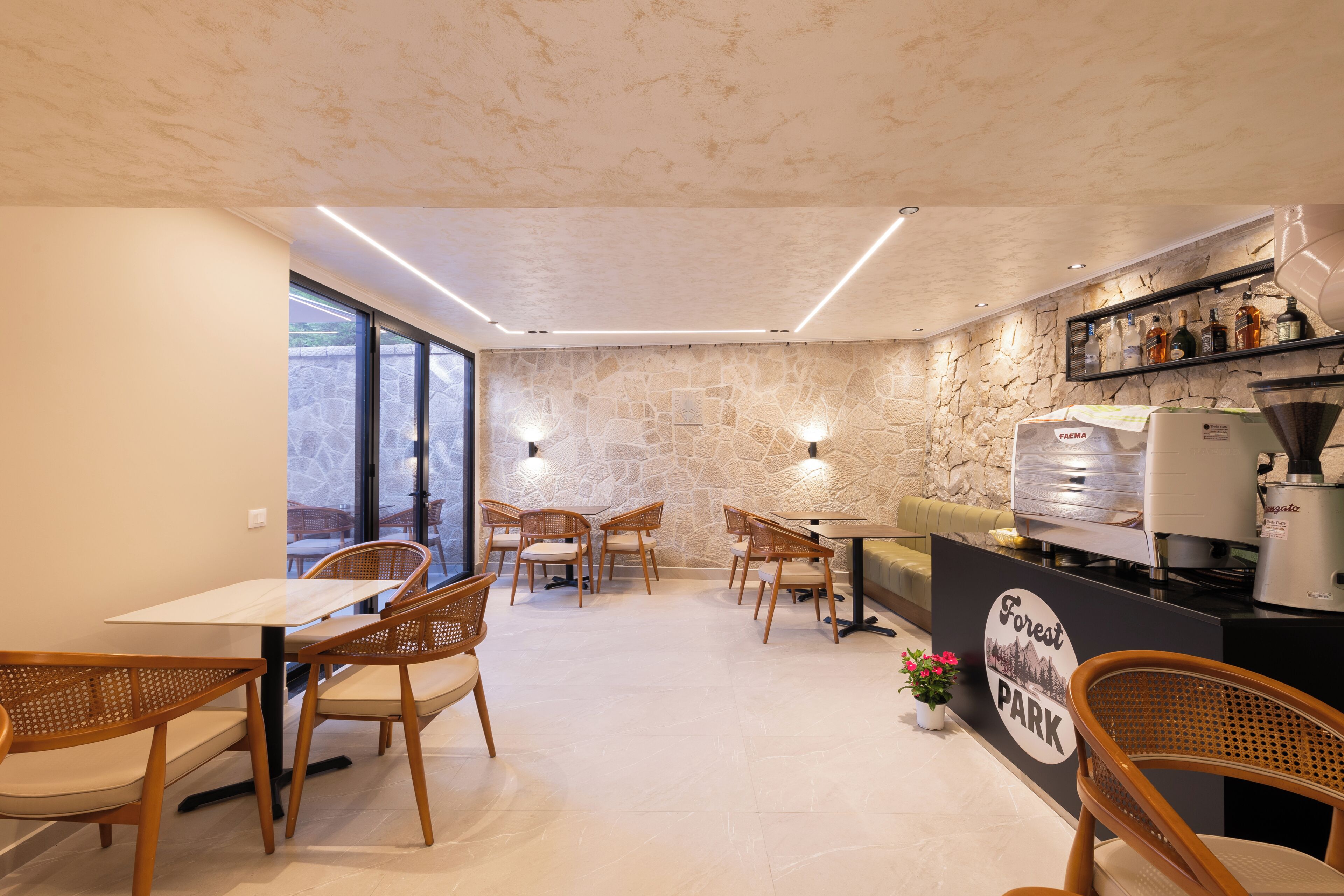Un restaurant avec un mur en pierre, des chaises en bois, un appareil à café et une enseigne indiquant « Forest Park ».