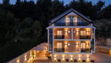 Una casa a più piani con un balcone, un muro in pietra e una zona salotto esterna.
