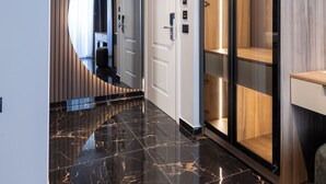 A modern hallway with a polished marble floor, a large mirror, a wardrobe with a glass door, and a built-in air conditioning unit. - Forest Park Hotel Krujë (Fushe-Kruje)