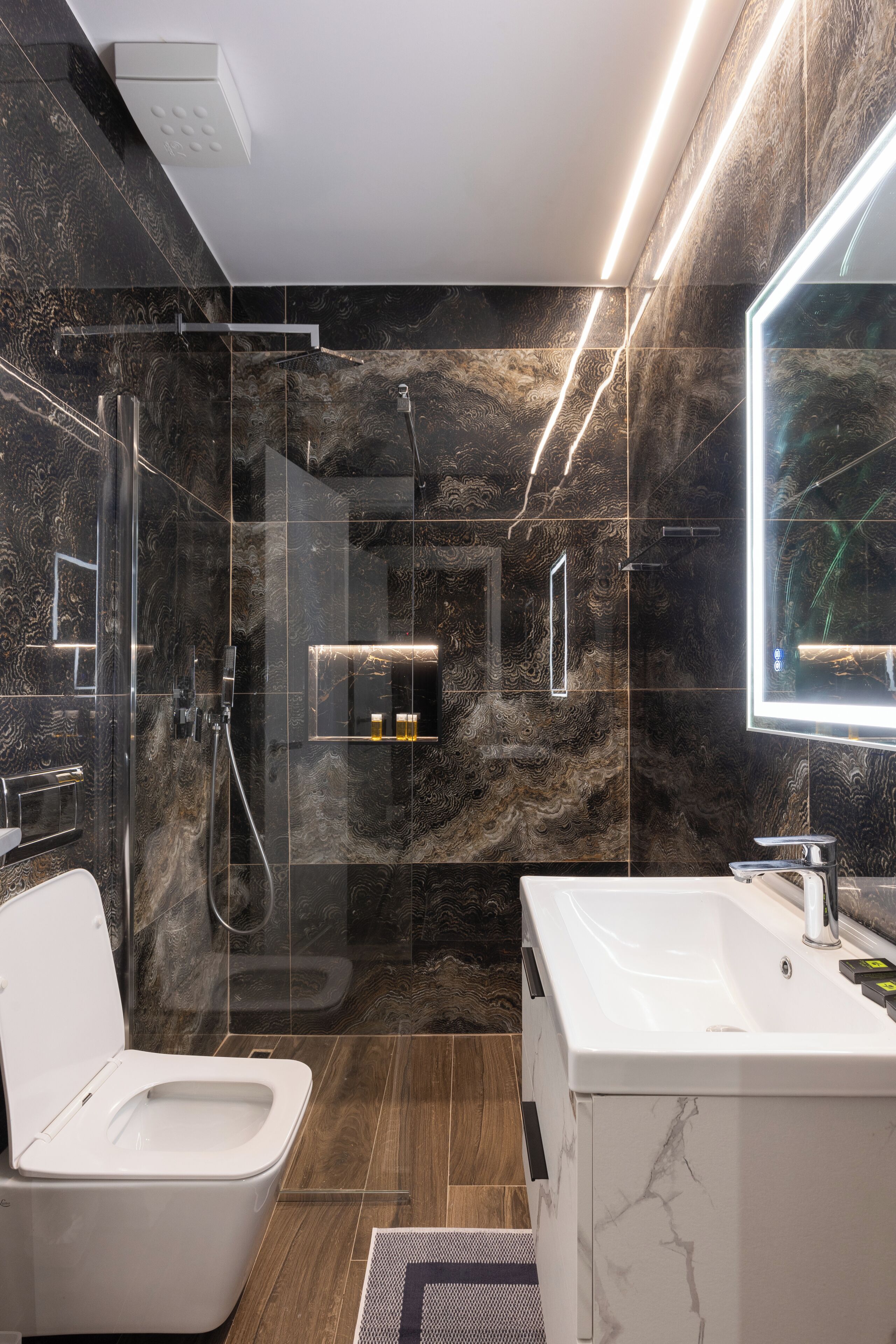 A modern bathroom with a glass-enclosed shower, a white toilet, and a large mirror.