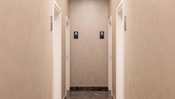 A corridor with marble flooring, beige walls, and doors marked with room numbers.