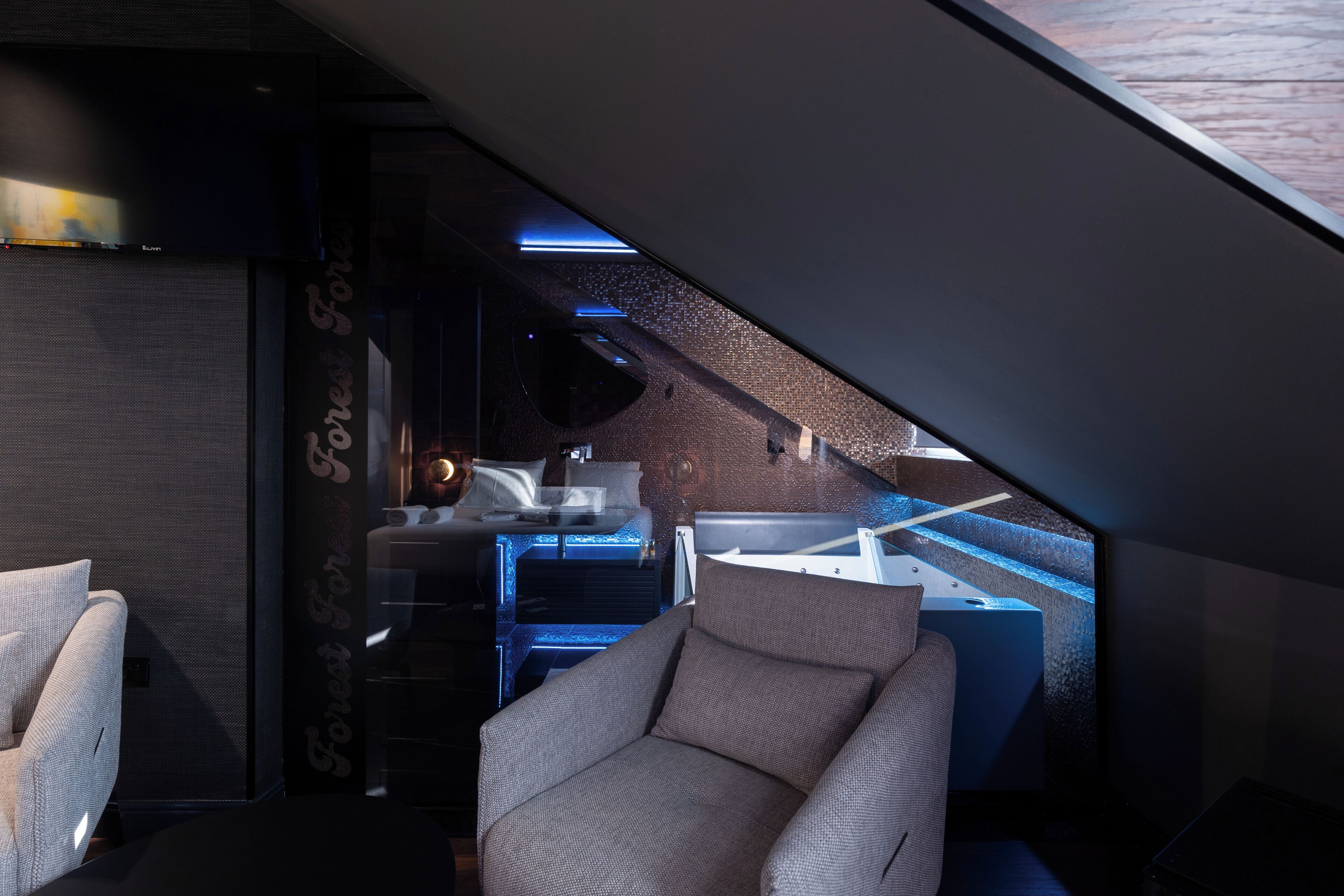 A modern interior with a sofa, a desk with a computer, and a view through a slanted ceiling.