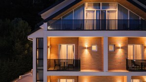 A multi-story building with wooden paneling, large windows, and outdoor seating areas. - Forest Park Hotel Krujë (Fushe-Kruje)