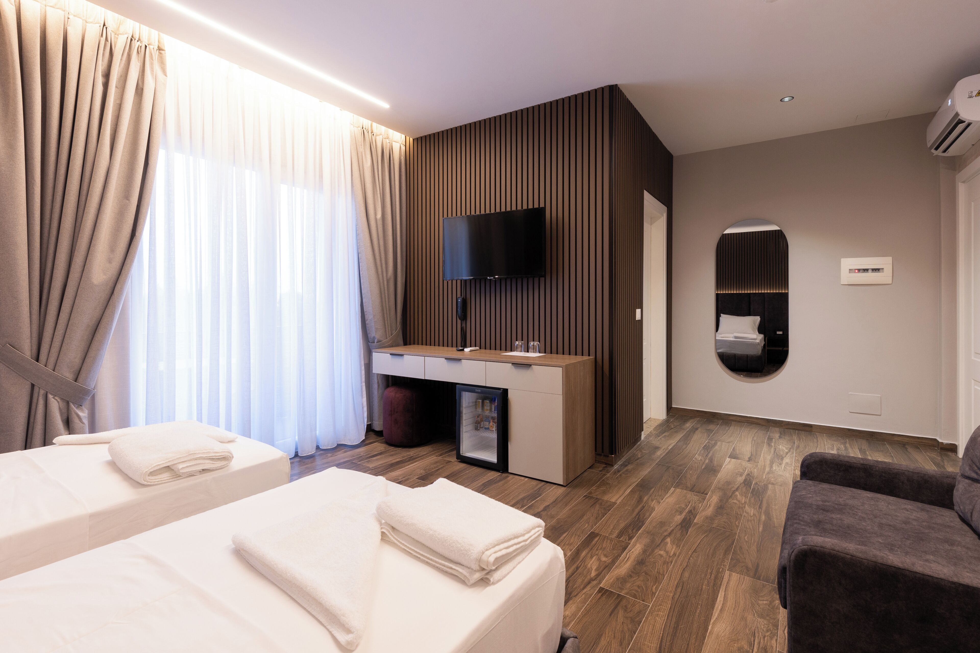 Habitació d'hotel amb dos llits, una taula de treball, una televisió i un mirall.