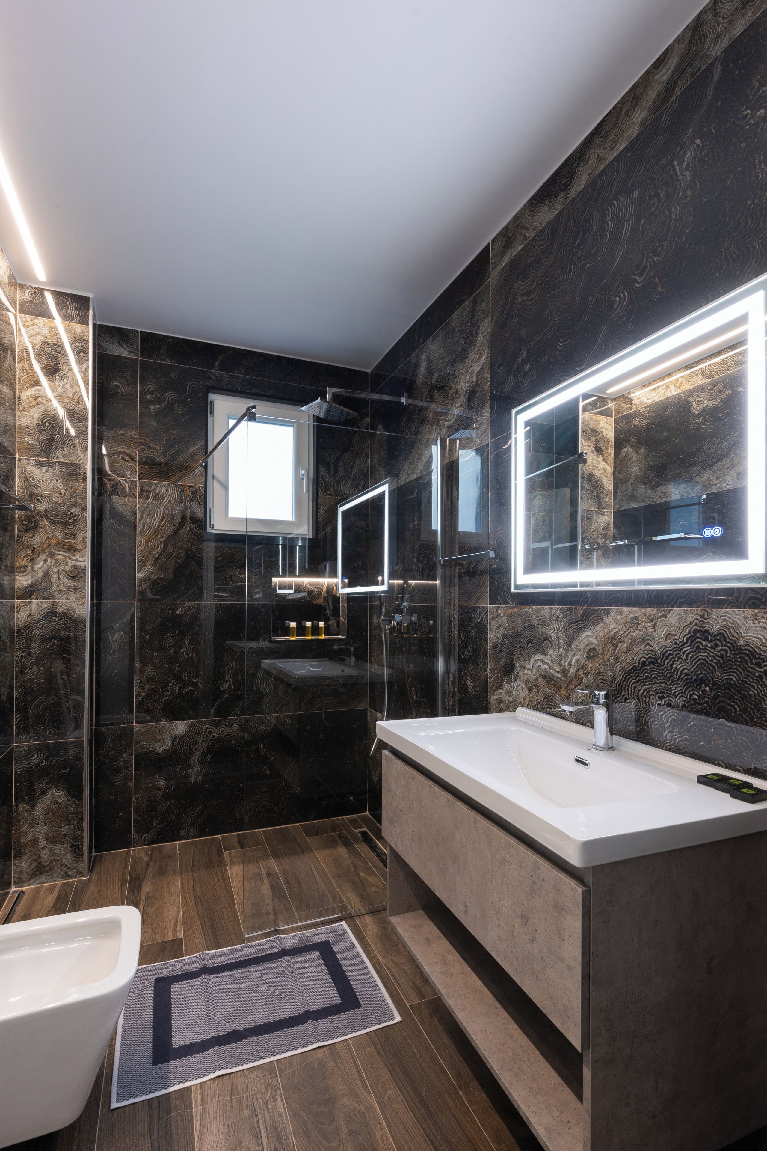 A modern bathroom with a large mirror, a bathtub, and a toilet.