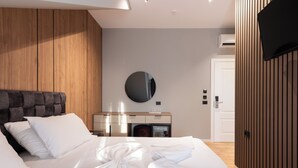 A modern hotel room with a large bed, a round mirror, a wooden headboard, a minibar, and a flat-screen TV. - Forest Park Hotel Krujë (Fushe-Kruje)