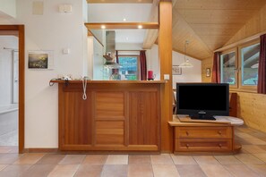 Ein Holzinnenraum mit einem Fernseher auf einem Schrank, einem Spiegel und einem Fenster mit Vorhängen.