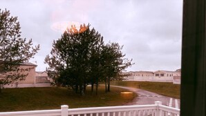 A view of a residential area with houses, a large tree, and a white fence. - Cabin Sleeps 4 With Beach Access & Parking (Lossiemouth)