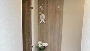 A hallway with a wooden wardrobe, a small bench, and a vase with flowers. - Cabin Sleeps 4 With Beach Access & Parking (Lossiemouth)