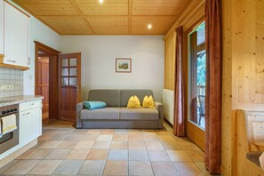 A cozy room with a sofa, a wooden ceiling, a window with curtains, and a kitchen area. - Apartment Himmelschlüssel 19 with Mountain View and Wi-Fi (Santa Valburga)