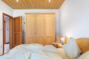 Ein Schlafzimmer mit einem Holzschrank, einem Nachttisch mit Lampe und einem Bett mit weißer Bettwäsche.