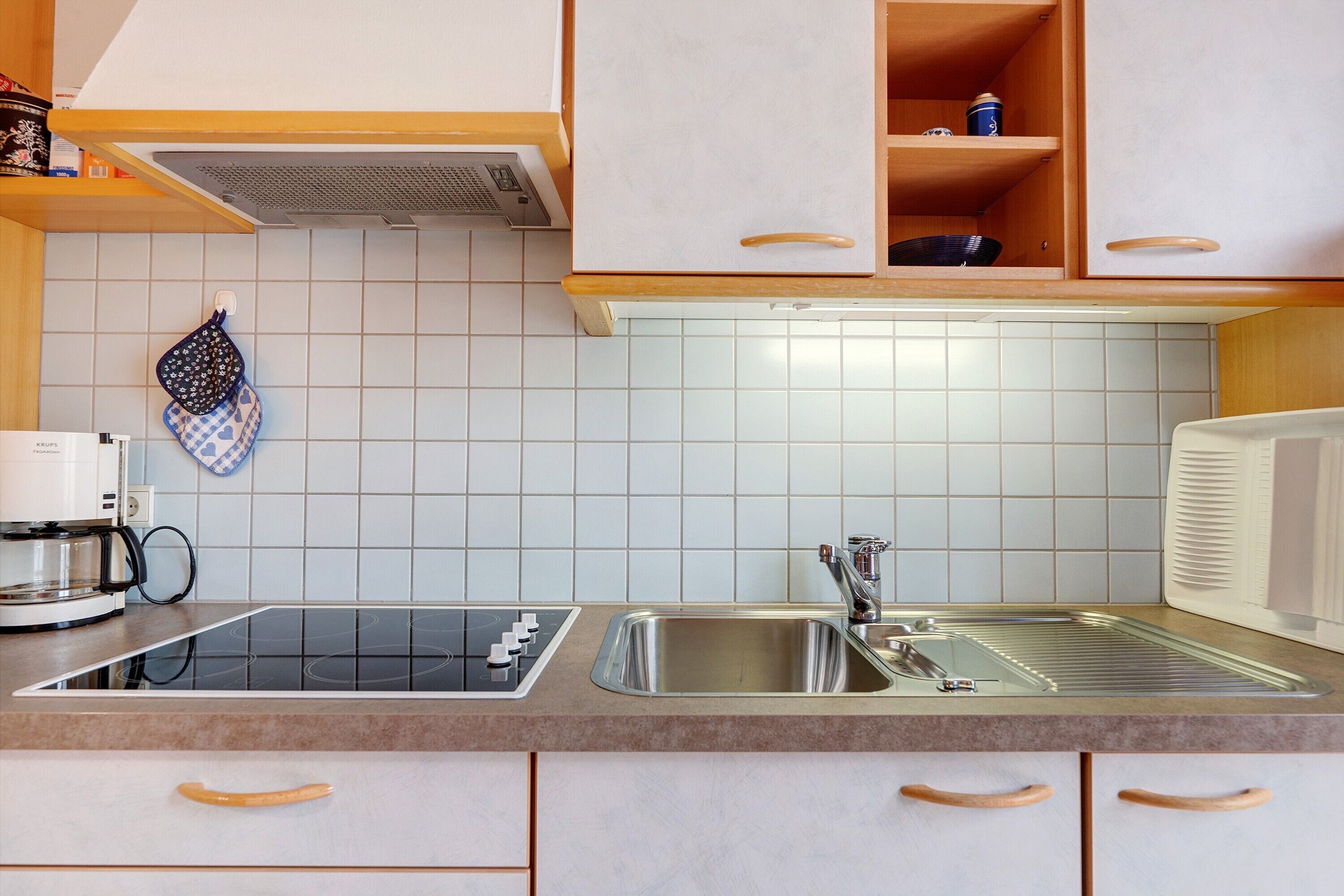 A kitchen with a stove, sink, and cabinets.