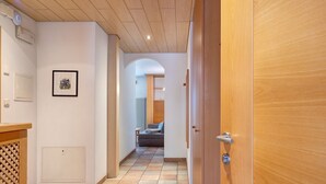 Un couloir avec une porte en bois, un radiateur et un tableau encadré accroché au mur.