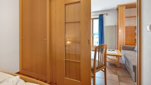 Une chambre à coucher avec une armoire en bois, un lit, une chaise et une petite table.