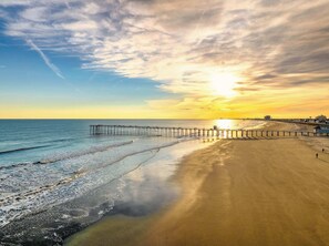 A beach with a wooden pier extending into the water, a clear sky, and a sunset. - 3br Newly Renovated Beach House Sleeps 10 (Ventnor City)