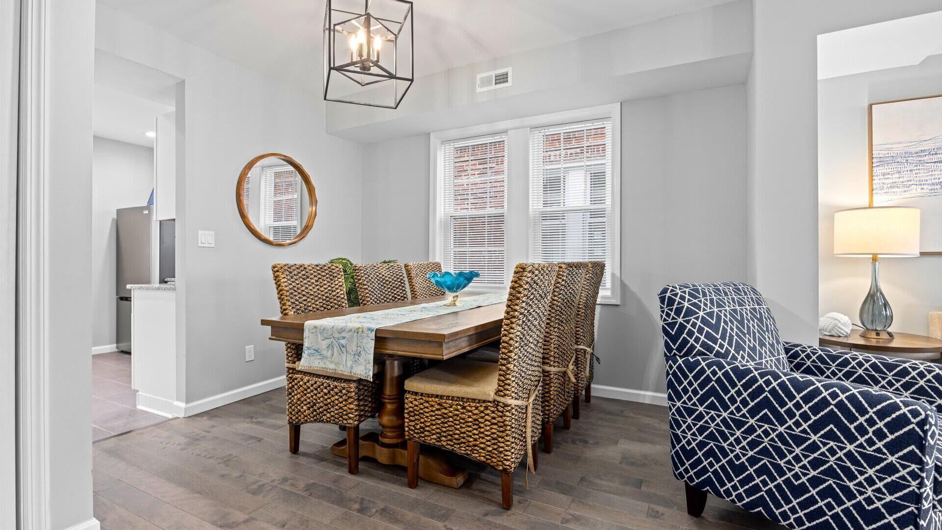 A dining area with a wooden table, woven chairs, and a blue patterned armchair.