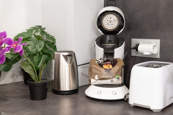 A kitchen counter with a coffee maker, a toaster, a kettle, and a potted plant. - Apartment 'Calme Elegant – Rer B – Paris' with Wi-Fi (Gentilly)