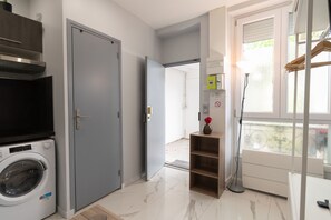 A laundry room with a washing machine, a gray door, and a window with a view. - Apartment 'Calme Elegant – Rer B – Paris' with Wi-Fi (Gentilly)