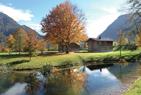 A rustic cabin by a calm lake with a mountain backdrop.