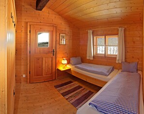 A wooden cabin room with a bed, bedside table, lamp, and a window. - Falkensteiner Camping Grubhof (Sankt Martin bei Lofer)