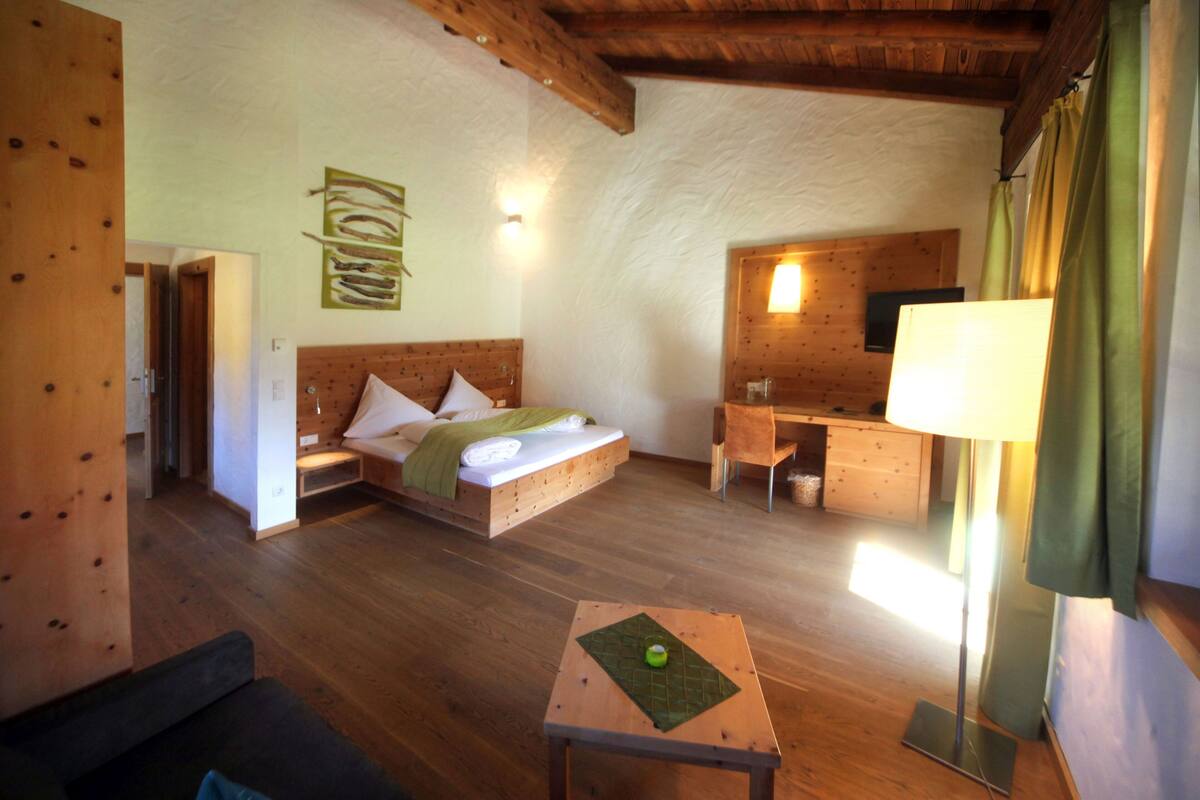 A room with a bed, a desk, a lamp, and a small table with a placemat.