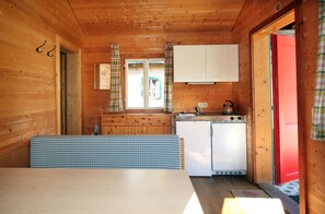 A compact cabin-style kitchen with a dining table, a refrigerator, and a sink.