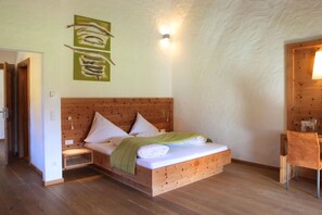 A wooden bed with pillows and a blanket, a wooden chair, and a wall-mounted light fixture. - Falkensteiner Camping Grubhof (Sankt Martin bei Lofer)