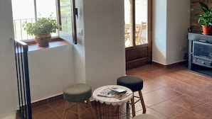 A room with a balcony, a small table with magazines, a potted plant, and a fireplace.
