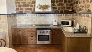 A kitchen with a stone wall, wooden cabinets, a built-in oven, a microwave, and a sink.