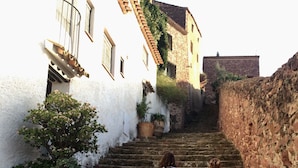 A staircase leading up to a building with white walls and a stone wall on one side.