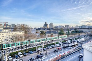 Une vue urbaine avec un train circulant sur une voie surélevée, des bâtiments et un ciel dégagé.