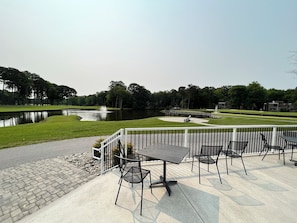 Une terrasse extérieure avec des tables et des chaises, un étang et un pont.
