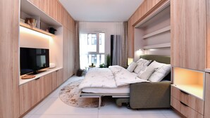 A modern bedroom with a bed, built-in TV, and wooden shelving. - Krymská Studios  (Prague)