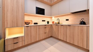 A modern kitchen with wooden cabinetry, a microwave, a kettle, and a sink. - Krymská Studios  (Prague)