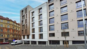 A modern building with multiple floors, large windows, and a parking area with a white van. - Krymská Studios  (Prague)