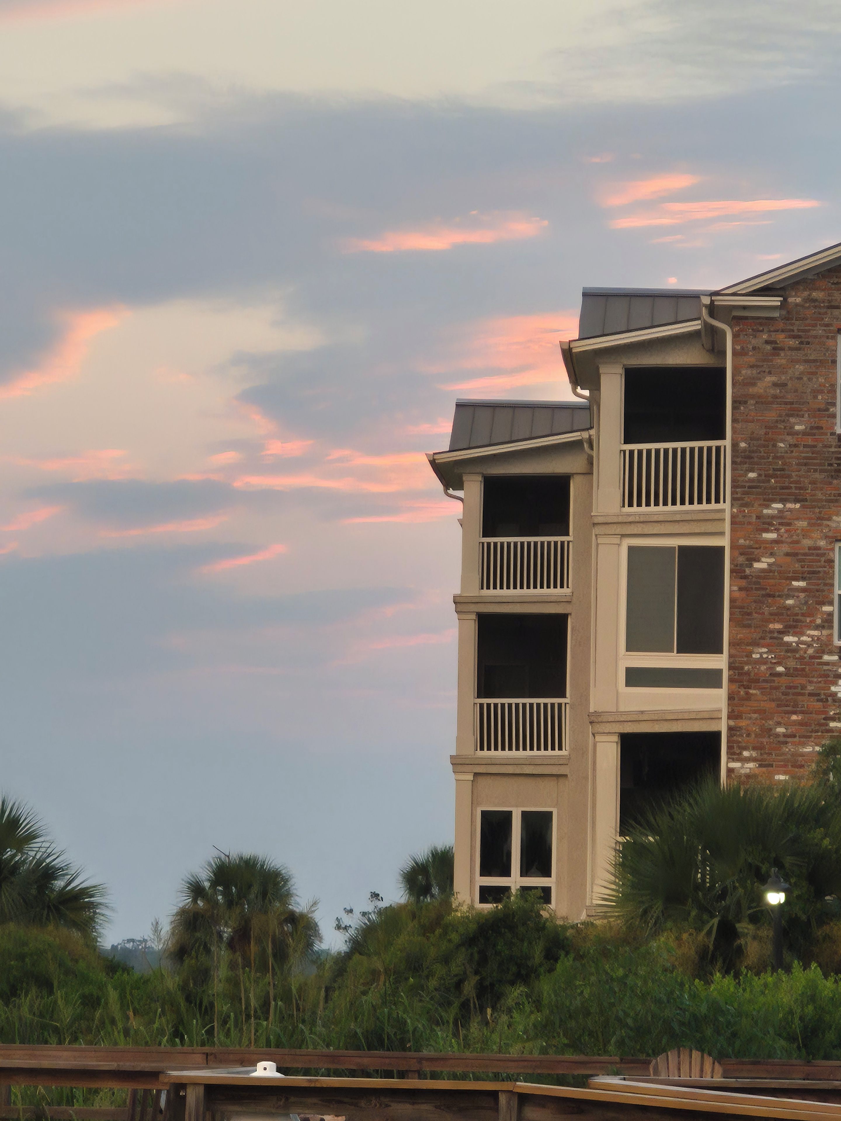 A multi-story building with balconies, surrounded by greenery.